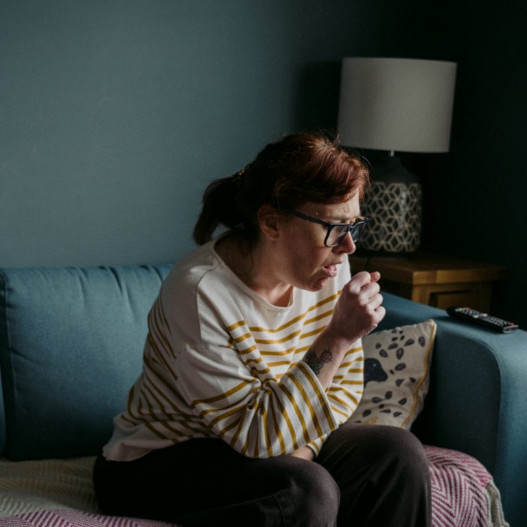 Frau auf Sofa, hustend